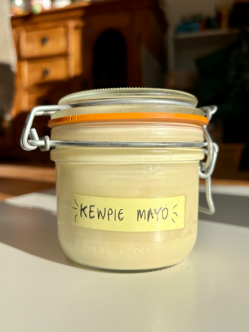 Glass jar with a label saying kewpie mayo on it.