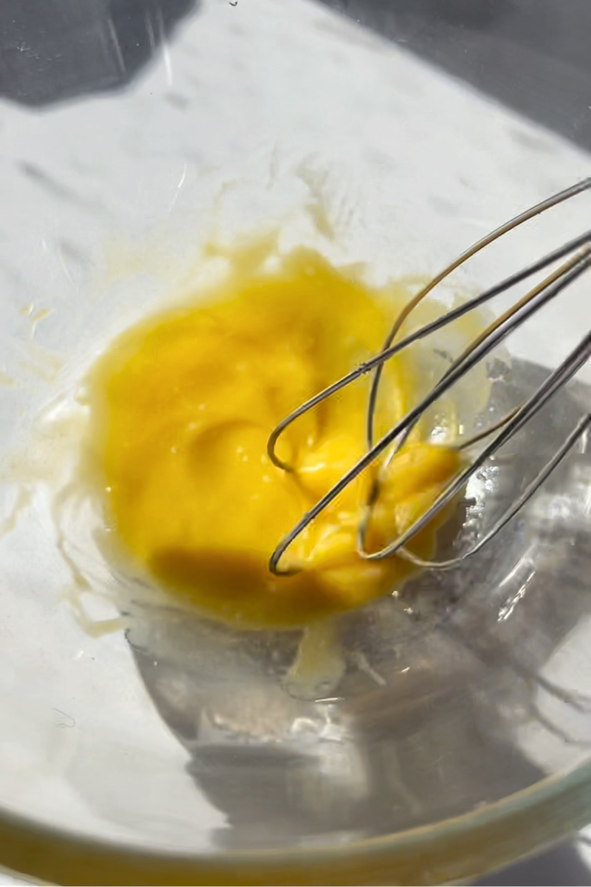 Whisking egg with a whisk in a bowl. 