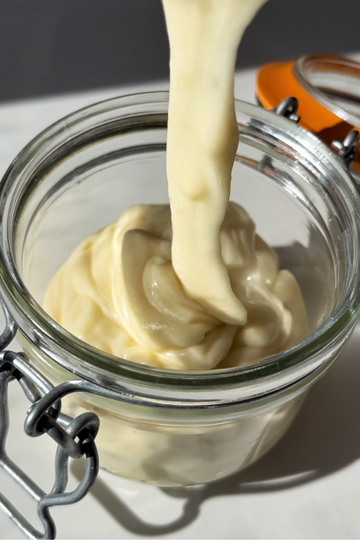 Pouring kewpie mayonnaise in a jar to store.