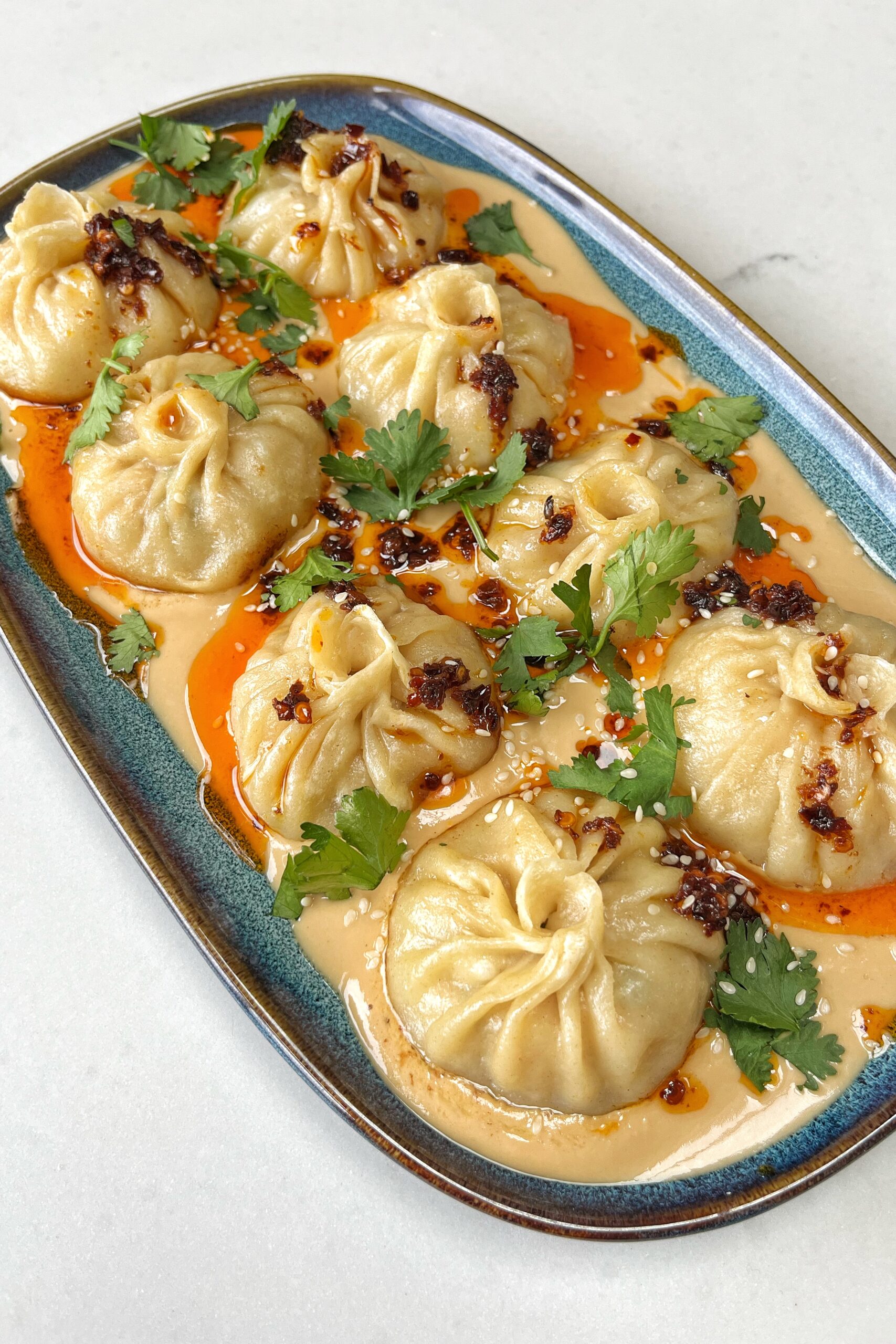 Chicken and pork dumplings on a bed of tahini chilli oil sauce