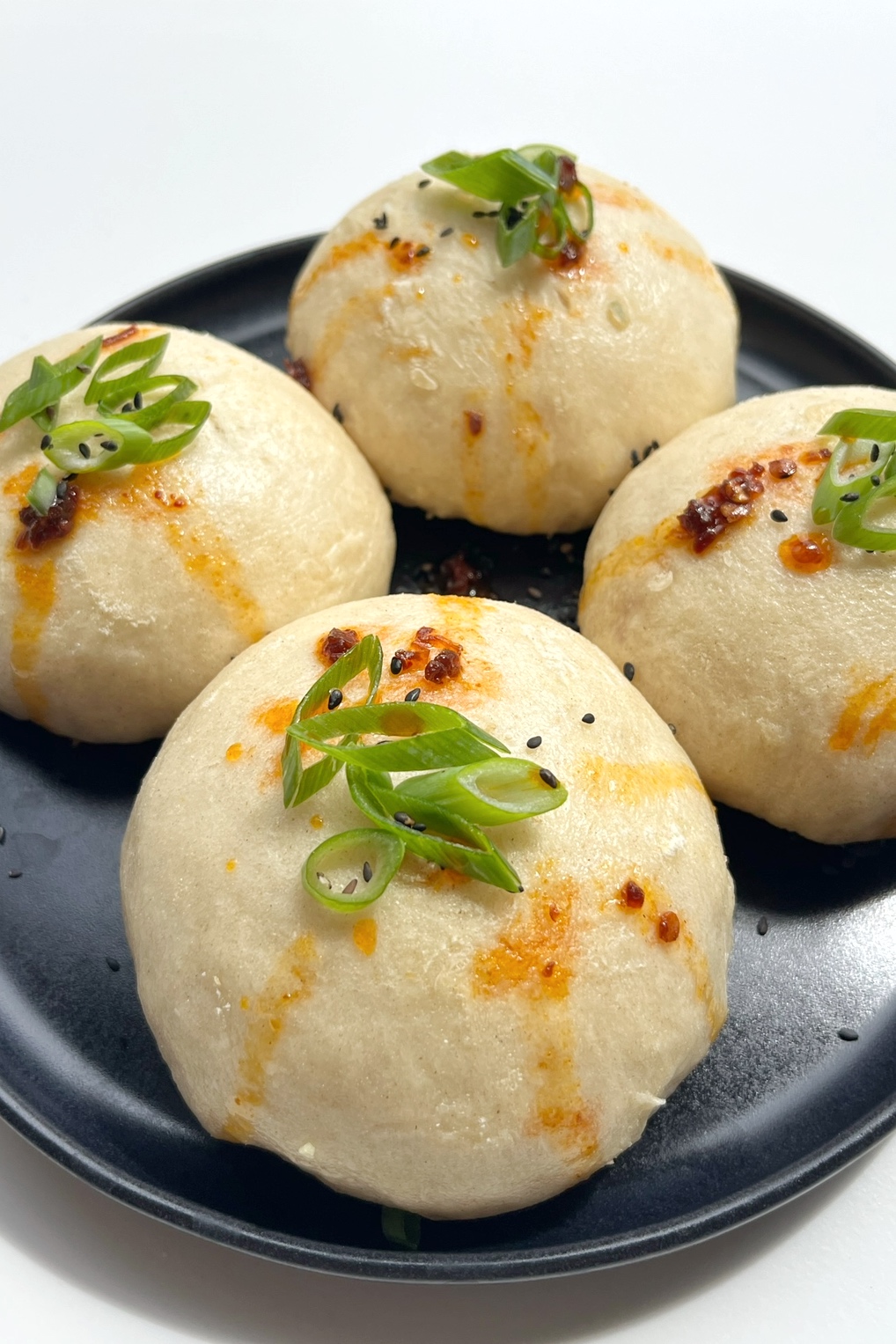 coconut bao (steamed buns) topped with spring onion and chilli oil.