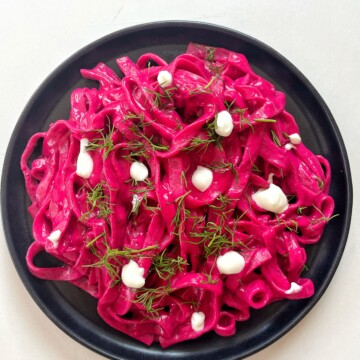 Pink pasta on a black plate.