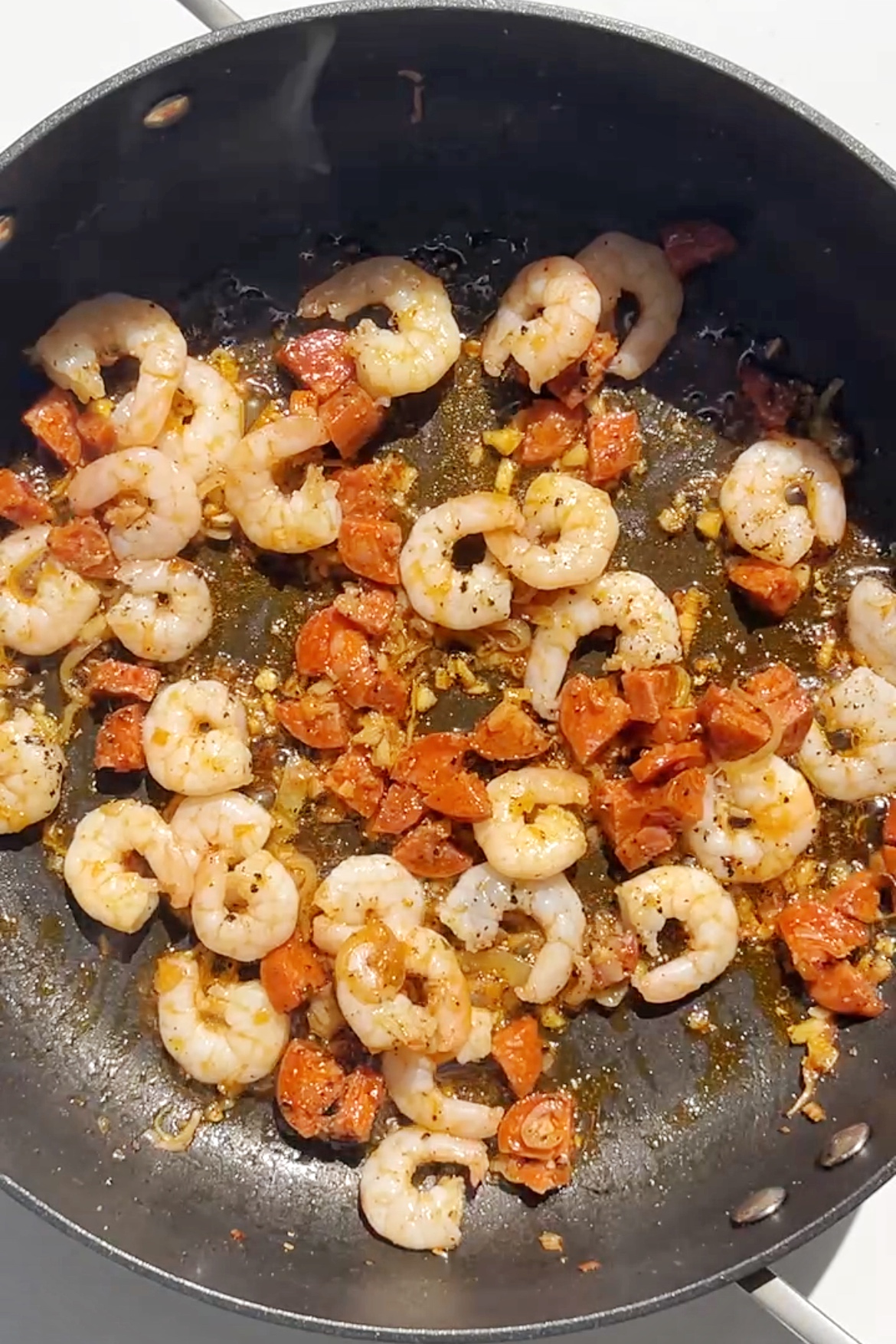 Frying prawns and chorizo in a pan.