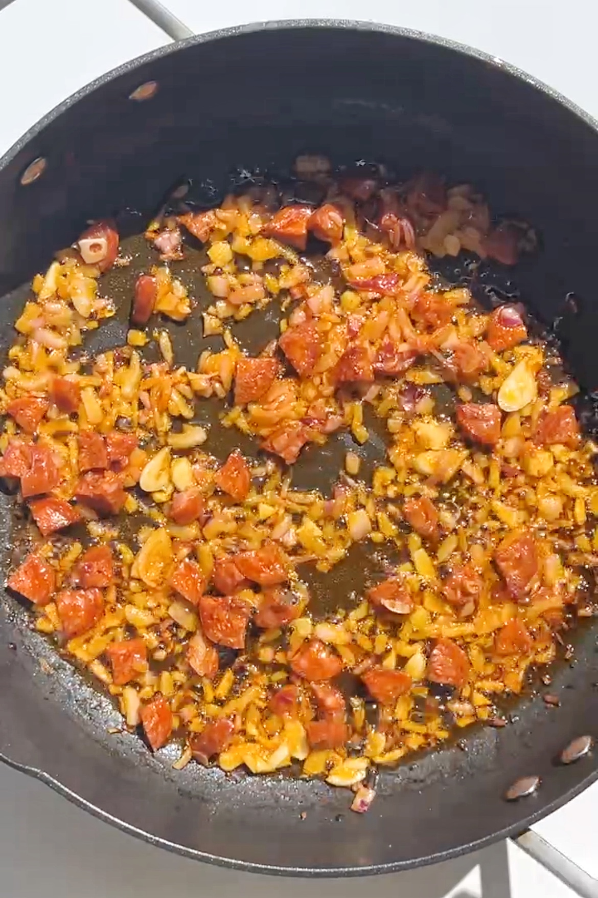 Frying garlic, onions, and chorizo in a pan.