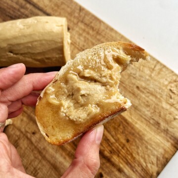 Close up of a person holding a piece of toast with espresso butter on it.