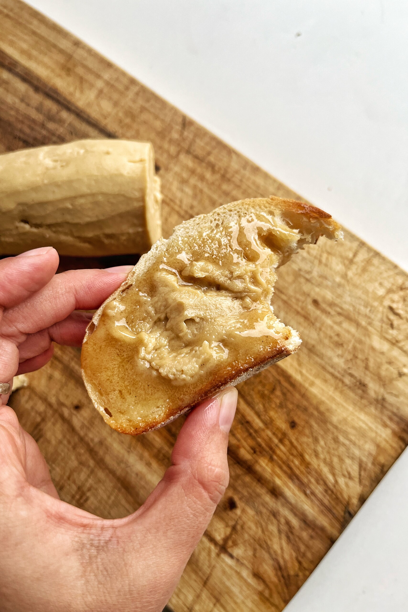Close up of a person holding a piece of toast with espresso butter on it.