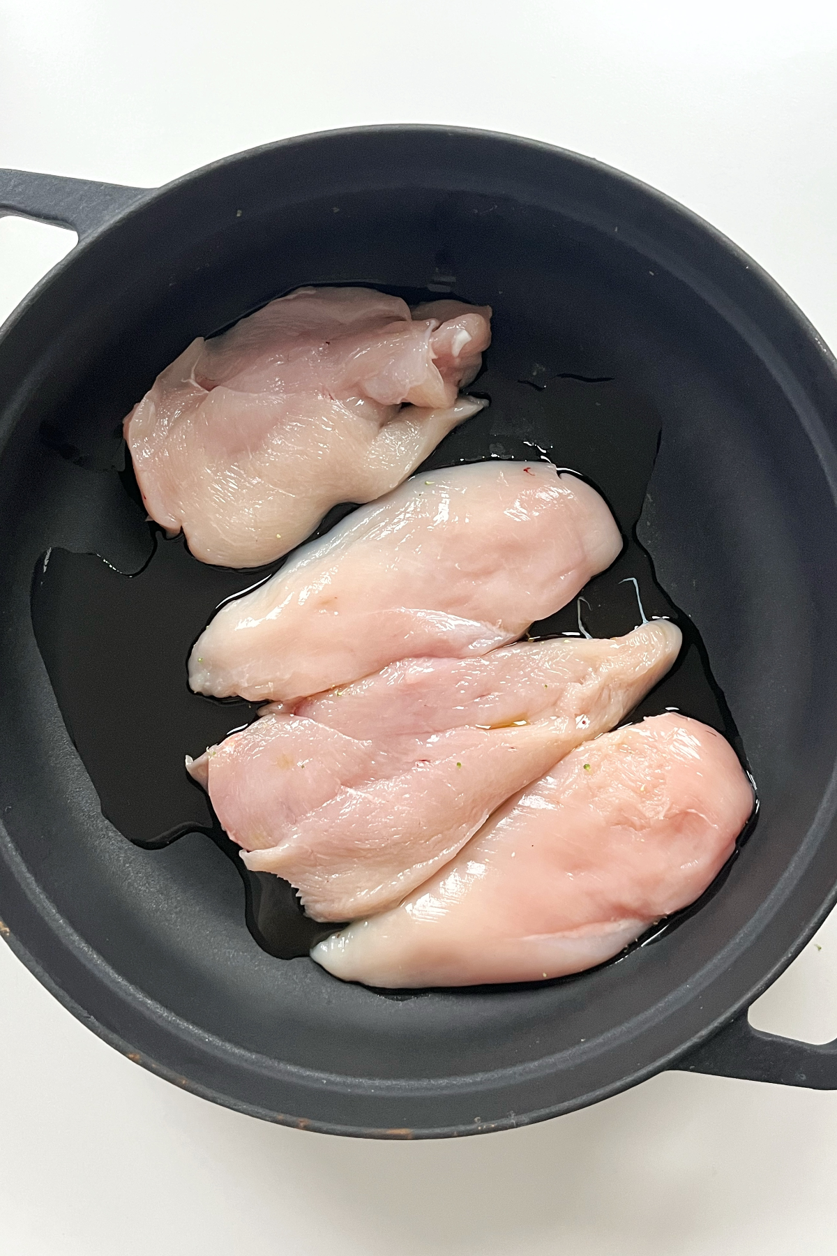 Black pan with 4 pieces of chicken inside. 