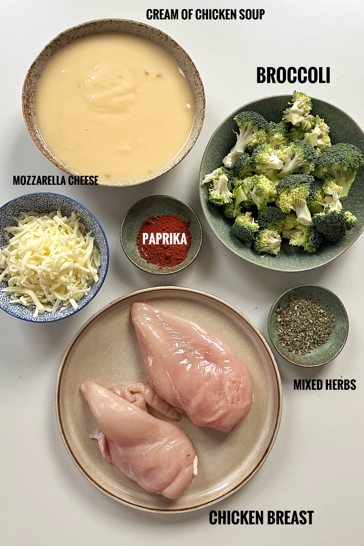 Image of all the ingredients needed for baked chicken with cream of chicken soup including cream of chicken soup, broccoli, mozzarella cheese, paprika, chicken breast, and mixed herbs.