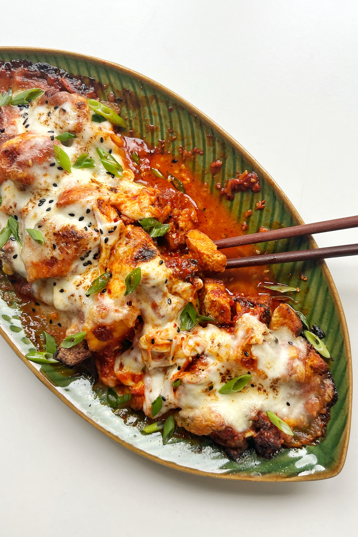 Green plate topped with fire chicken with chopstick. 