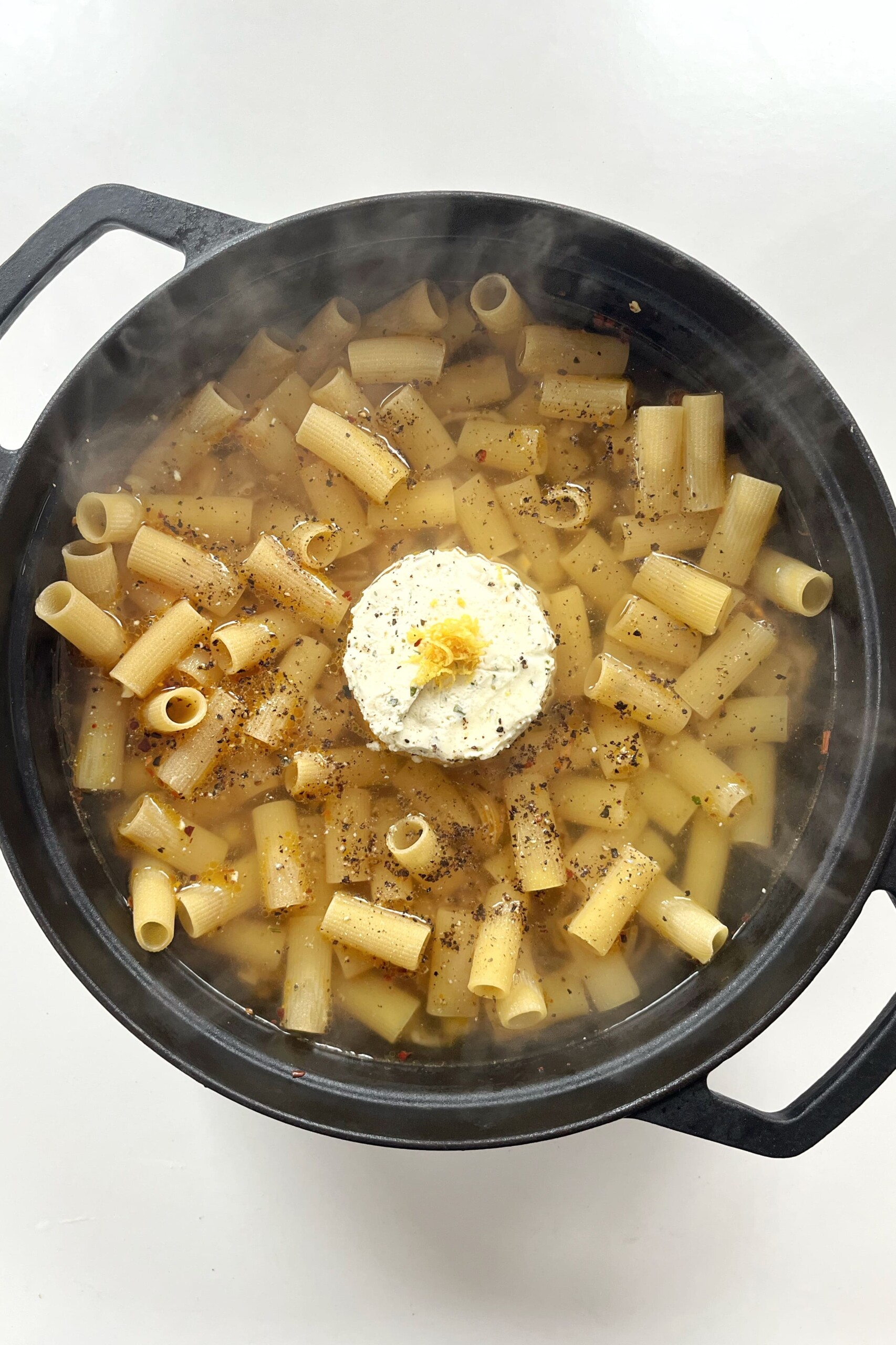 Pasta in a black pan with Boursin and lemon zest.