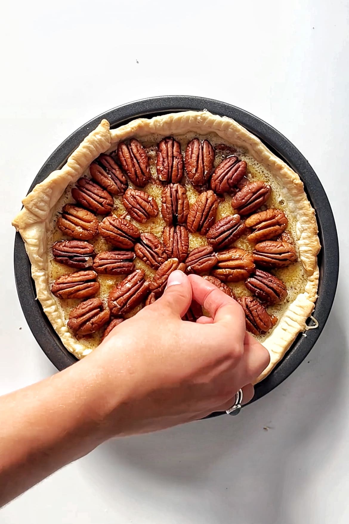 Placing pecans down onto a pie. 