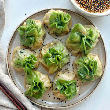Plate of green and white dumplings with a dipping sauce.