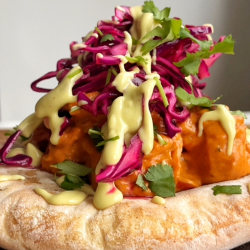 naan bread topped with butter curry, red cabbage, coriander, and avocado drizzle.