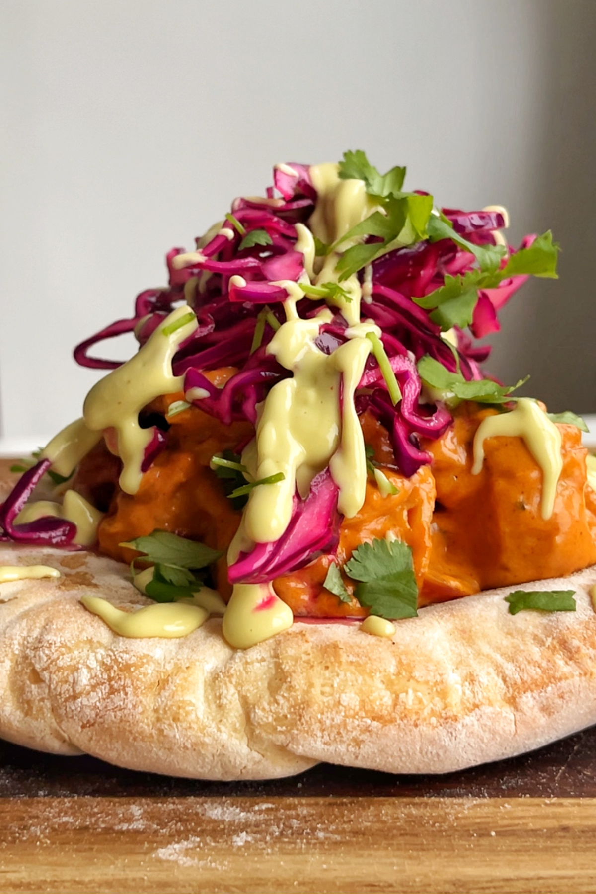 naan bread topped with butter curry, red cabbage, coriander, and avocado drizzle.
