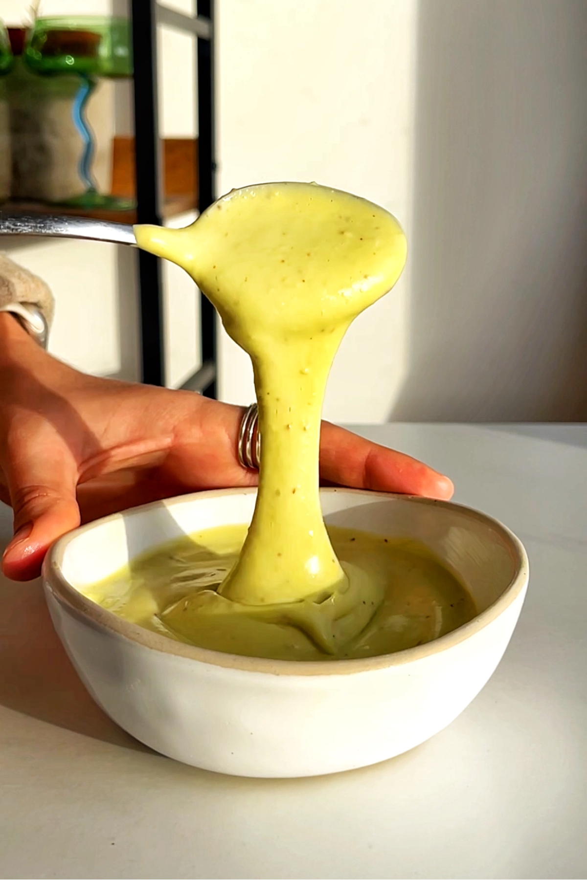 Avocado drizzle sauce in a white small bowl.
