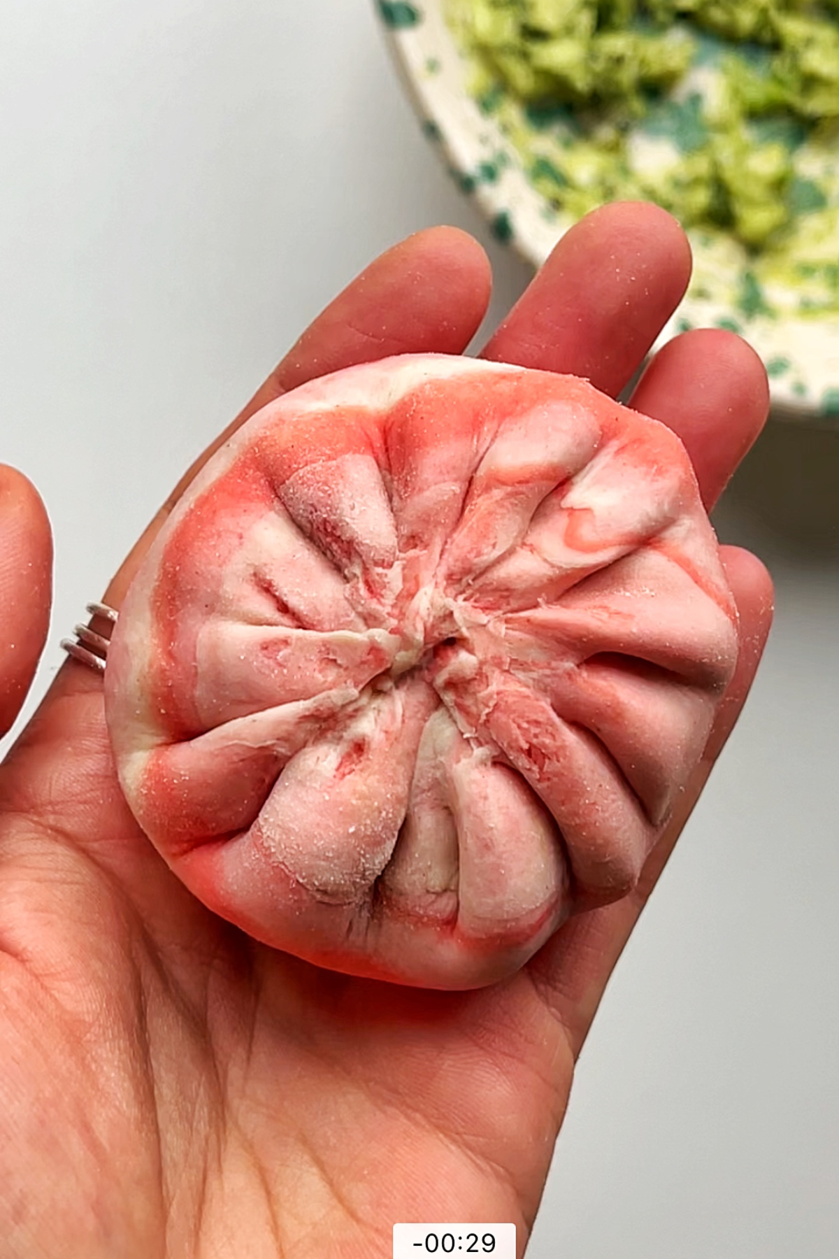 Pink and white dumpling held in lady's hand.