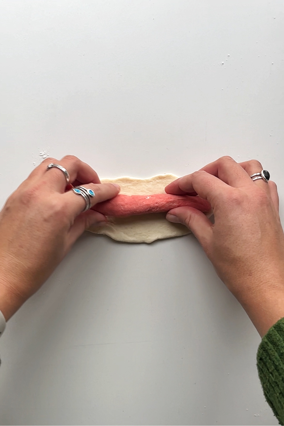 Placing pink log dough into the white piece of dough. 