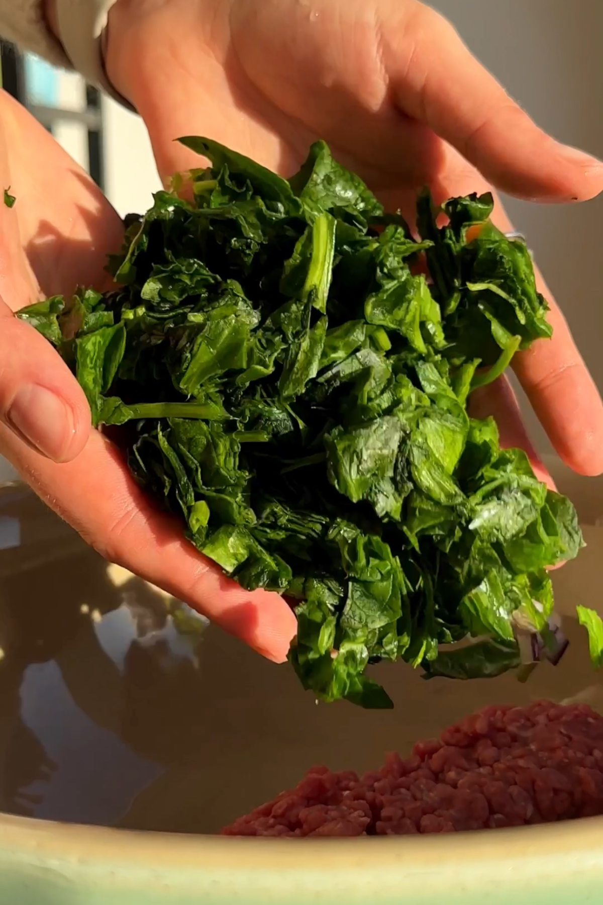 Adding spinach to a dumpling filling mixture. 