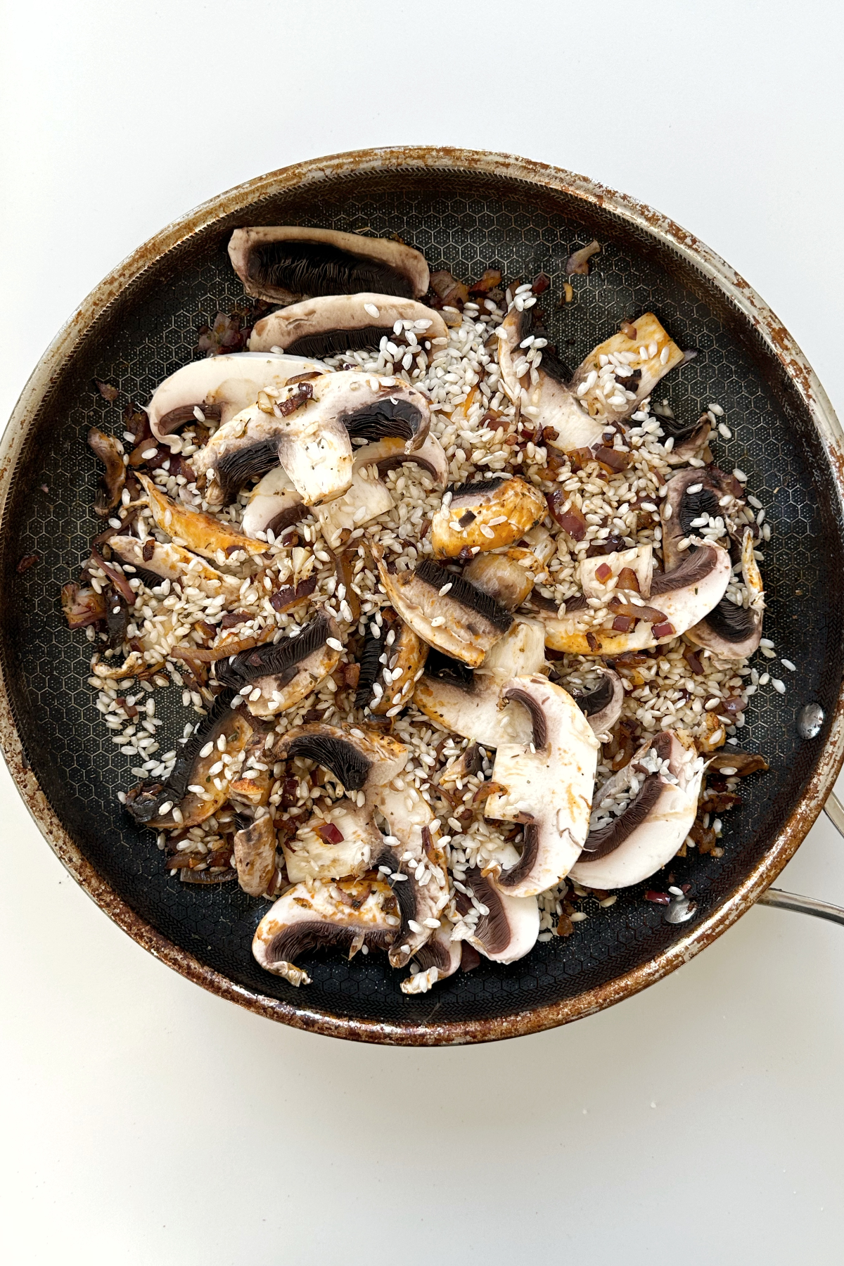 Frying garlic, red onion, and mushrooms in a black frying pan. 
