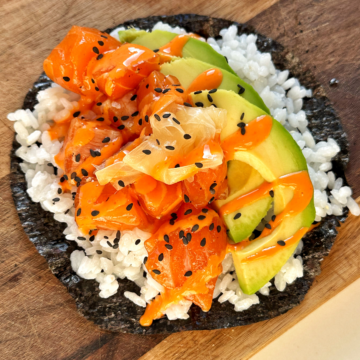 Sushi taco on a chopping board with avocado and salmon.