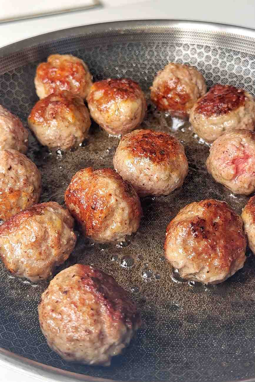 Frying meatballs in pan.