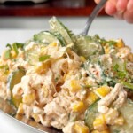 Creamy chicken cucumber salad on a metal tray on a white background.