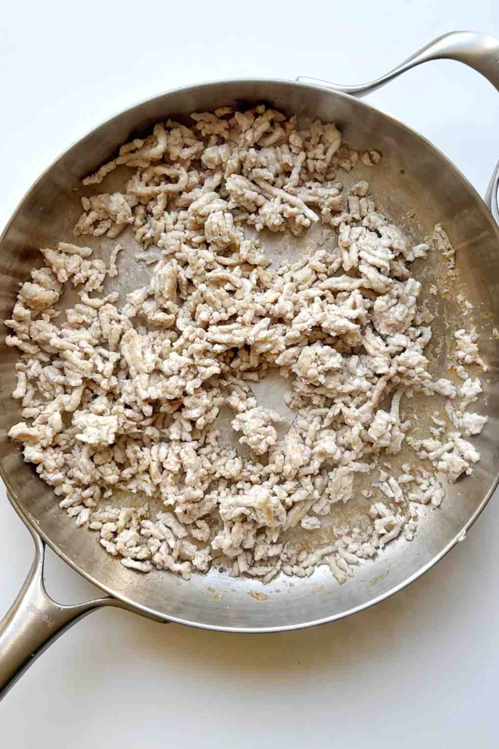 Frying chicken mince in metal pan.