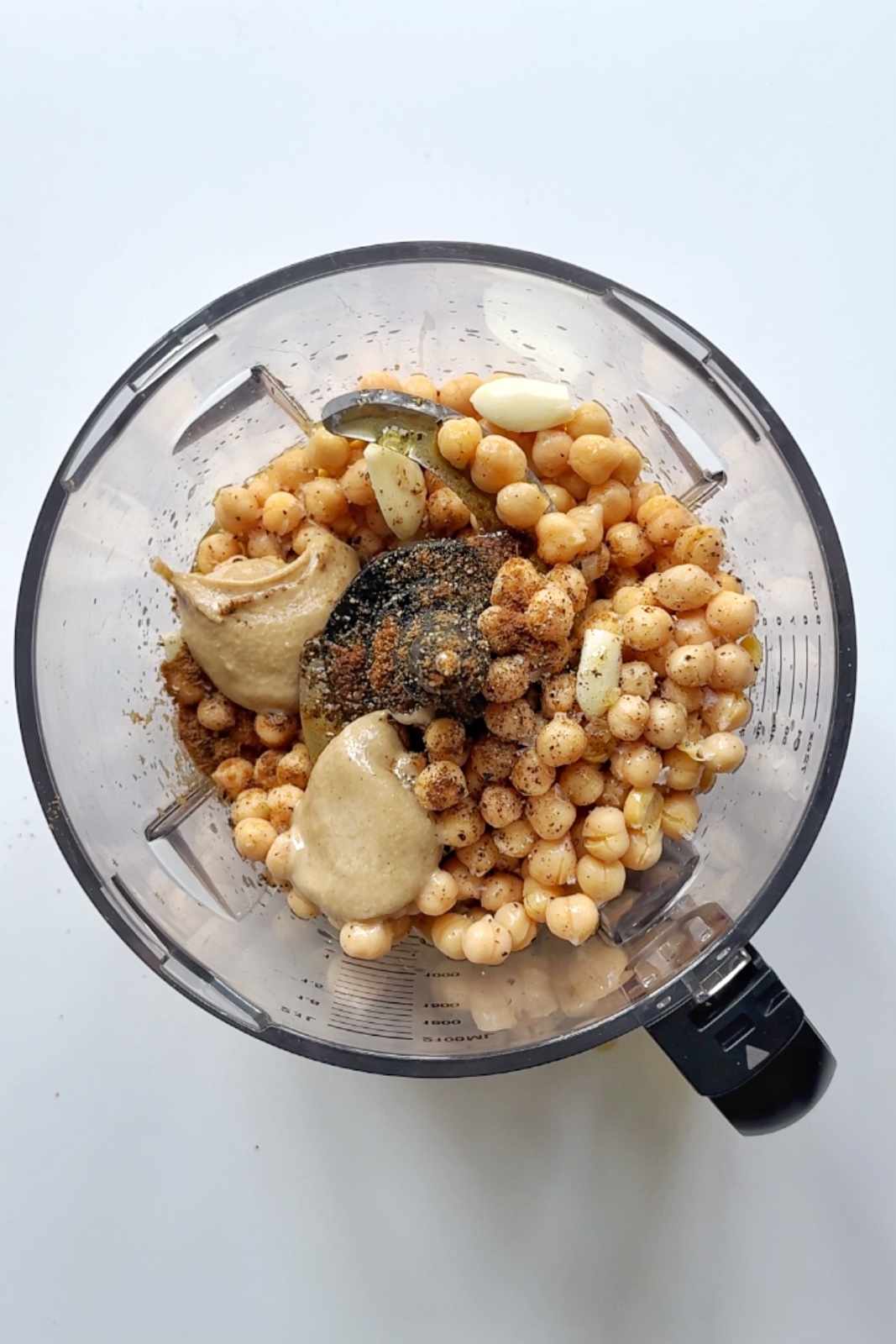 Hummus ingredients in a food processor on white background.