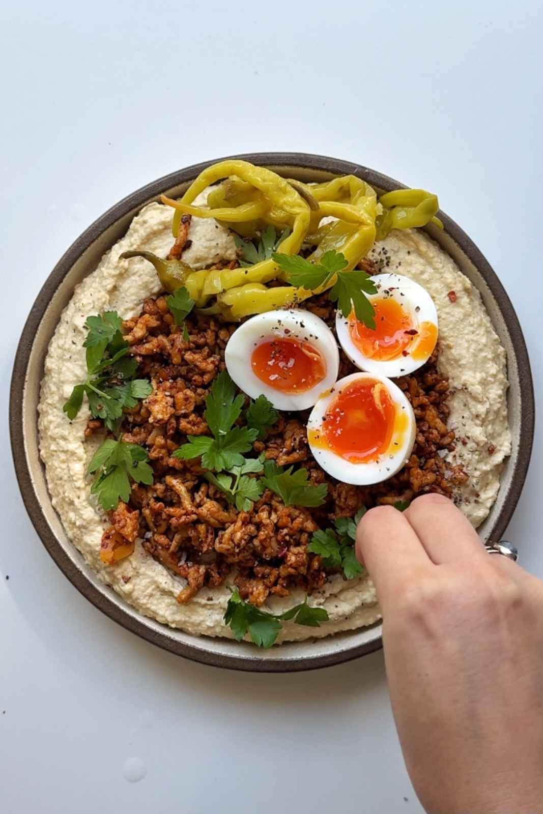 Garnishing the chicken hummus bowl.