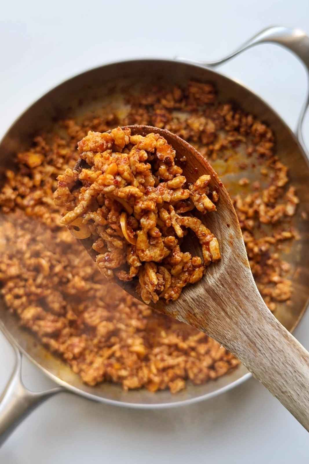 Frying ground chicken in pan with harissa paste.
