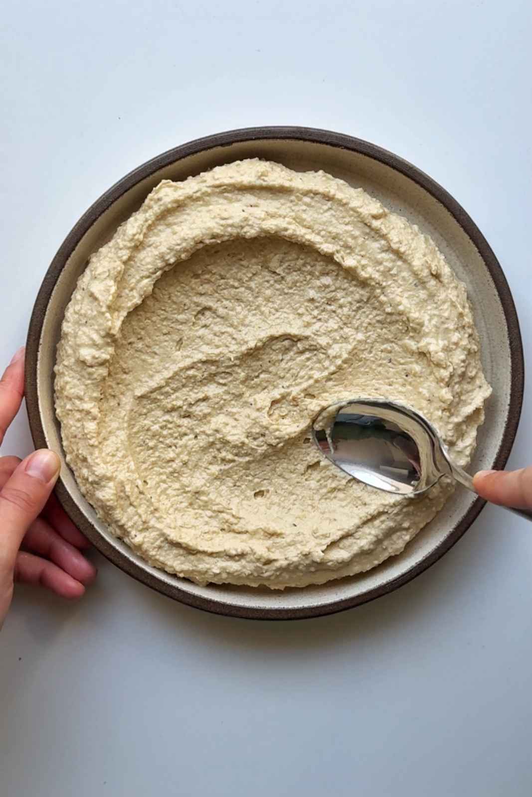 Serving up hummus on plate.