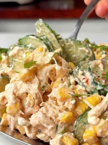 Creamy chicken cucumber salad on a metal tray on a white background.