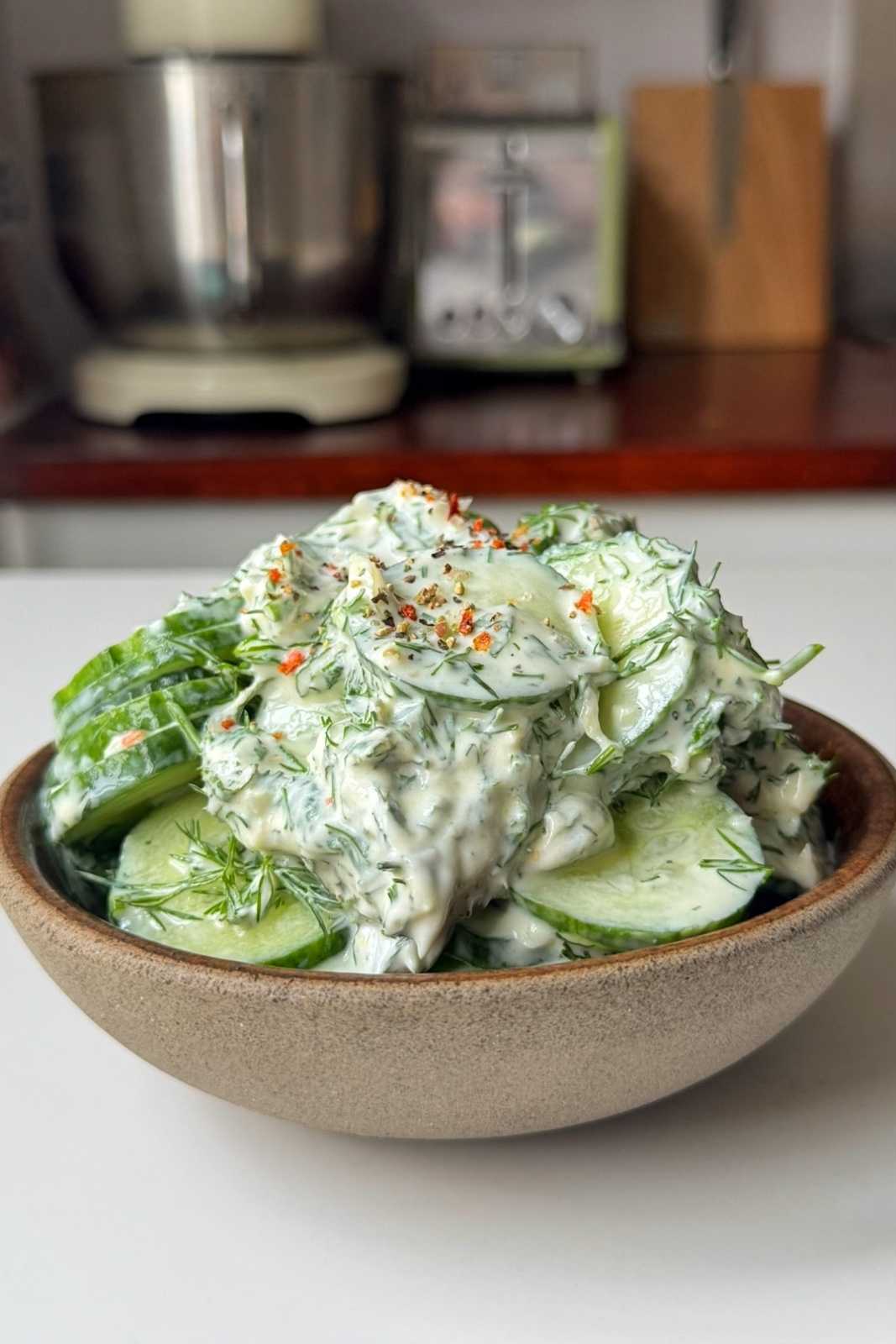 Cucumber dill salad in a brown bowl.