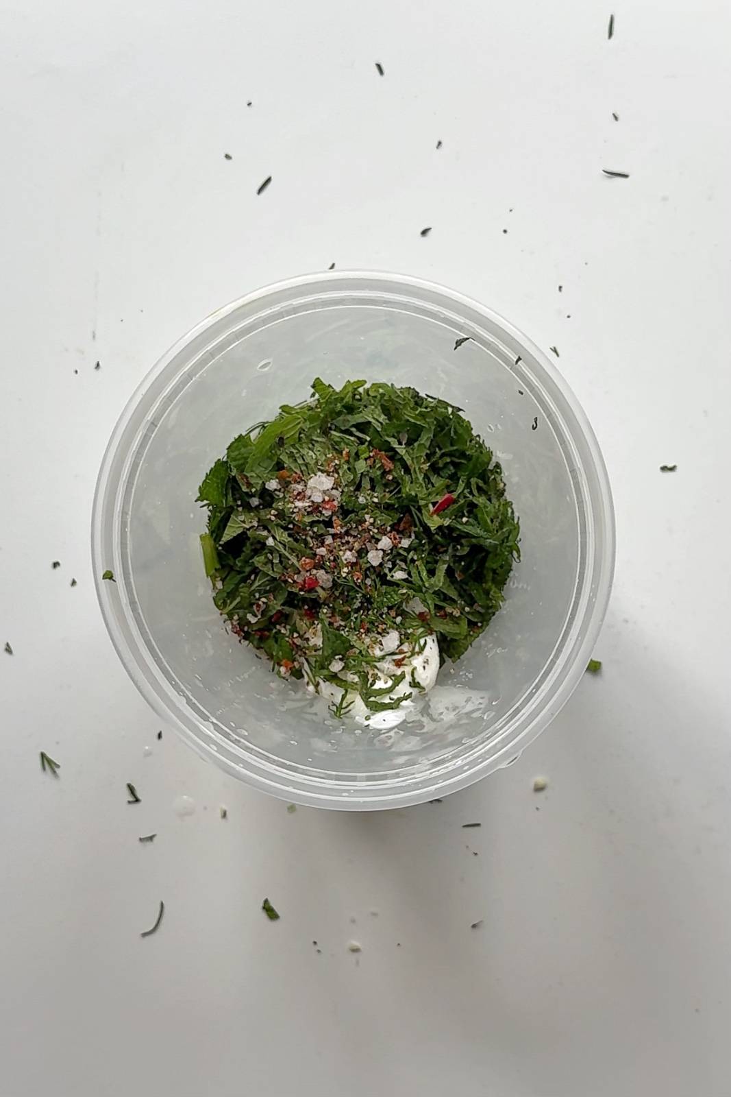 Plastic tupperware filled with a dill dressing.