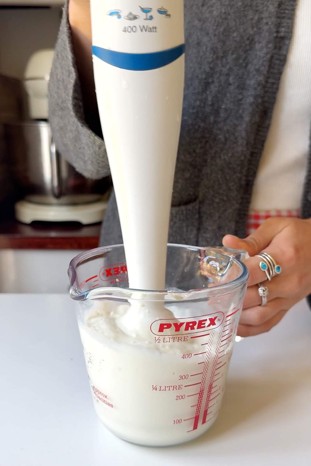 Using an immersion blender to blend soft tofu into a creamy smooth sauce in a Pyrex measuring jug