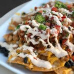 Close up view of plate of nachos with beef, cheese and jalapeño nacho toppings.