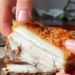 Close-up of a thick slice of air-fried pork belly, showing the juicy layers of meat and a perfectly golden, bubbly, and crispy crackling skin.