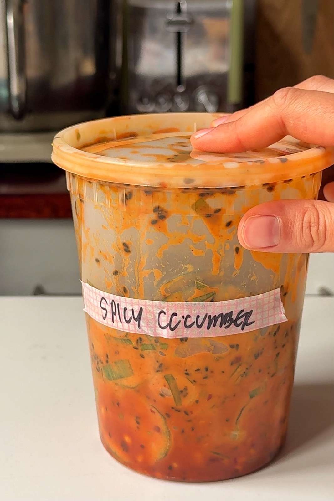 Spicy cucumber salad in plastic food container.