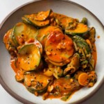 Spicy cucumber salad in white bowl.