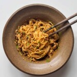 brown bowl with chopsticks filled with Thai-style peanut butter noodles