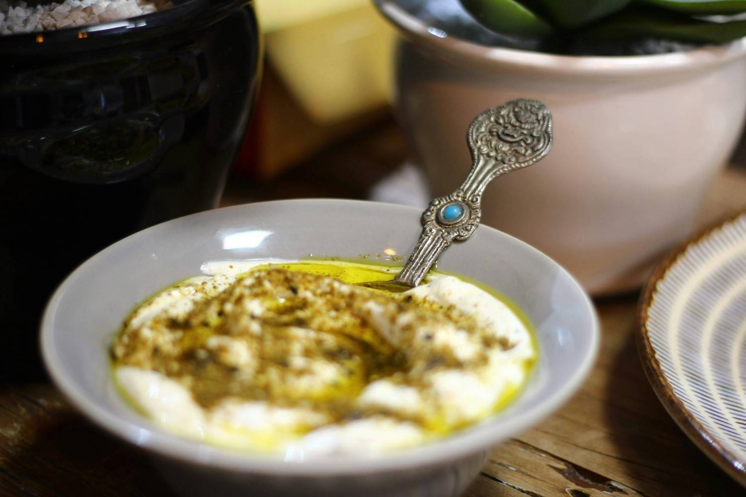 Bowl of labneh drizzled with olive oil and sprinkled with za'atar with an ornate silver spoon