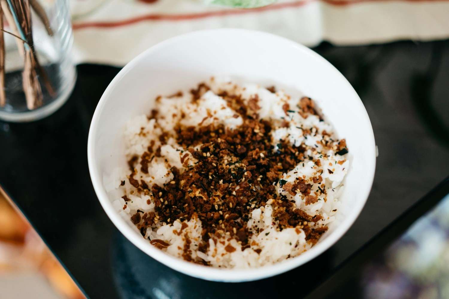 Bowl of rice topped with furikake seasoning showing sesame seeds, seaweed, and bonito flakes