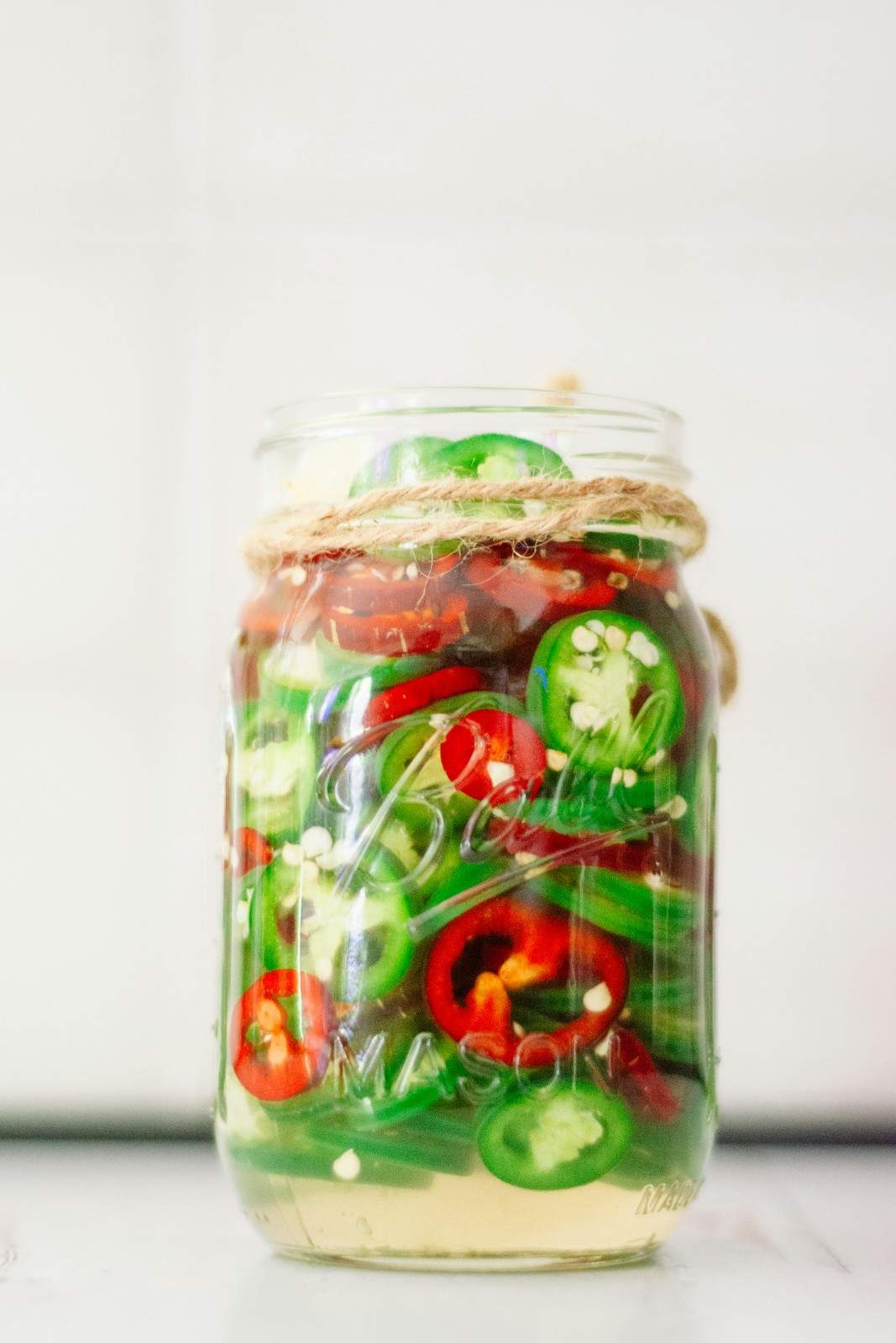 Mason jar filled with sliced pickled jalapeños and red chili peppers in brine