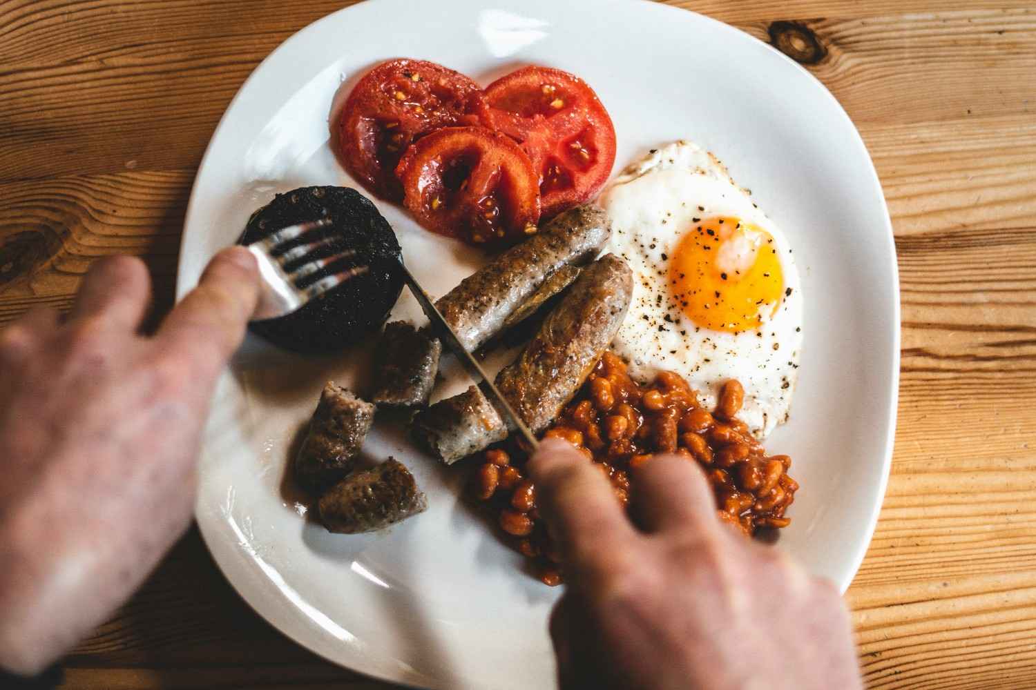 Full English breakfast with black pudding, a fried egg, sausages, baked beans, and tomatoes (the inspiration for a British-style bagel topping)