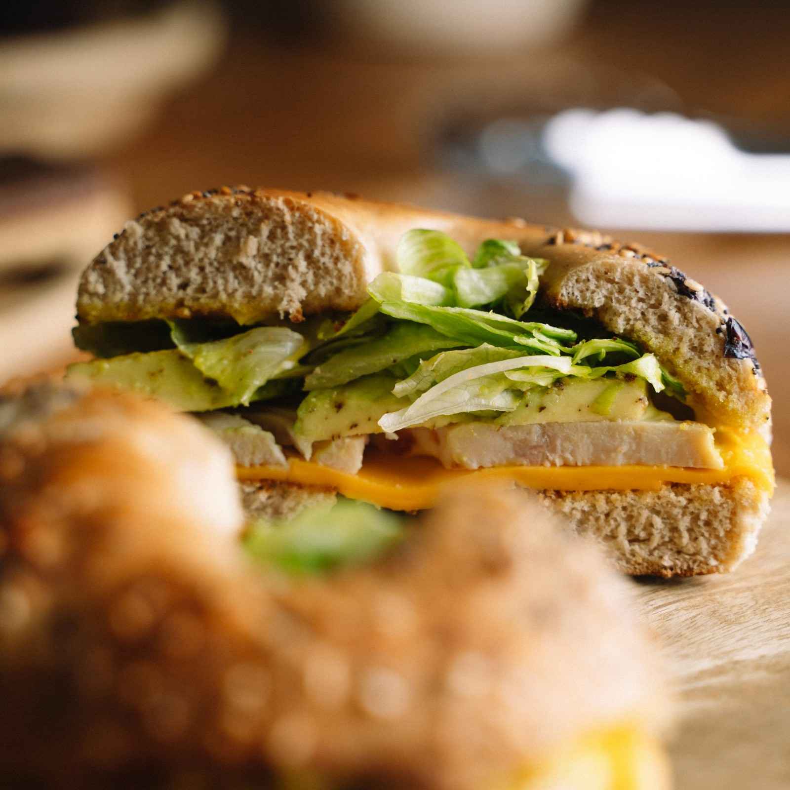 Turkey and cheese bagel sandwich with lettuce on a whole wheat everything bagel, sliced in half
