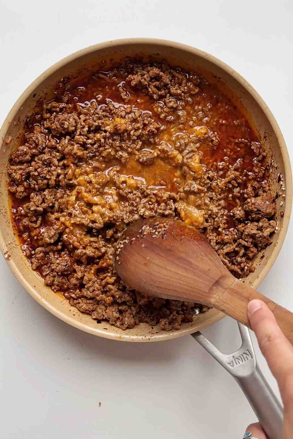 Seasoned taco ground beef cooking in a skillet with a wooden spoon, perfect for a baked potato bar topping.