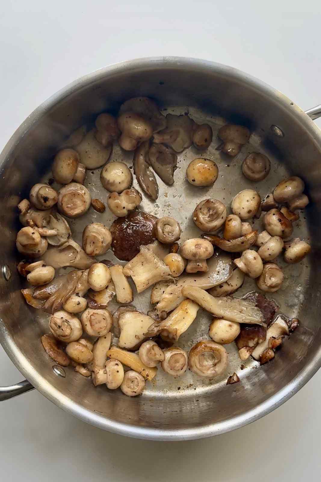 Butter-sautéed mushrooms turning golden in a stainless steel pan, an earthy and savory baked potato bar topping.