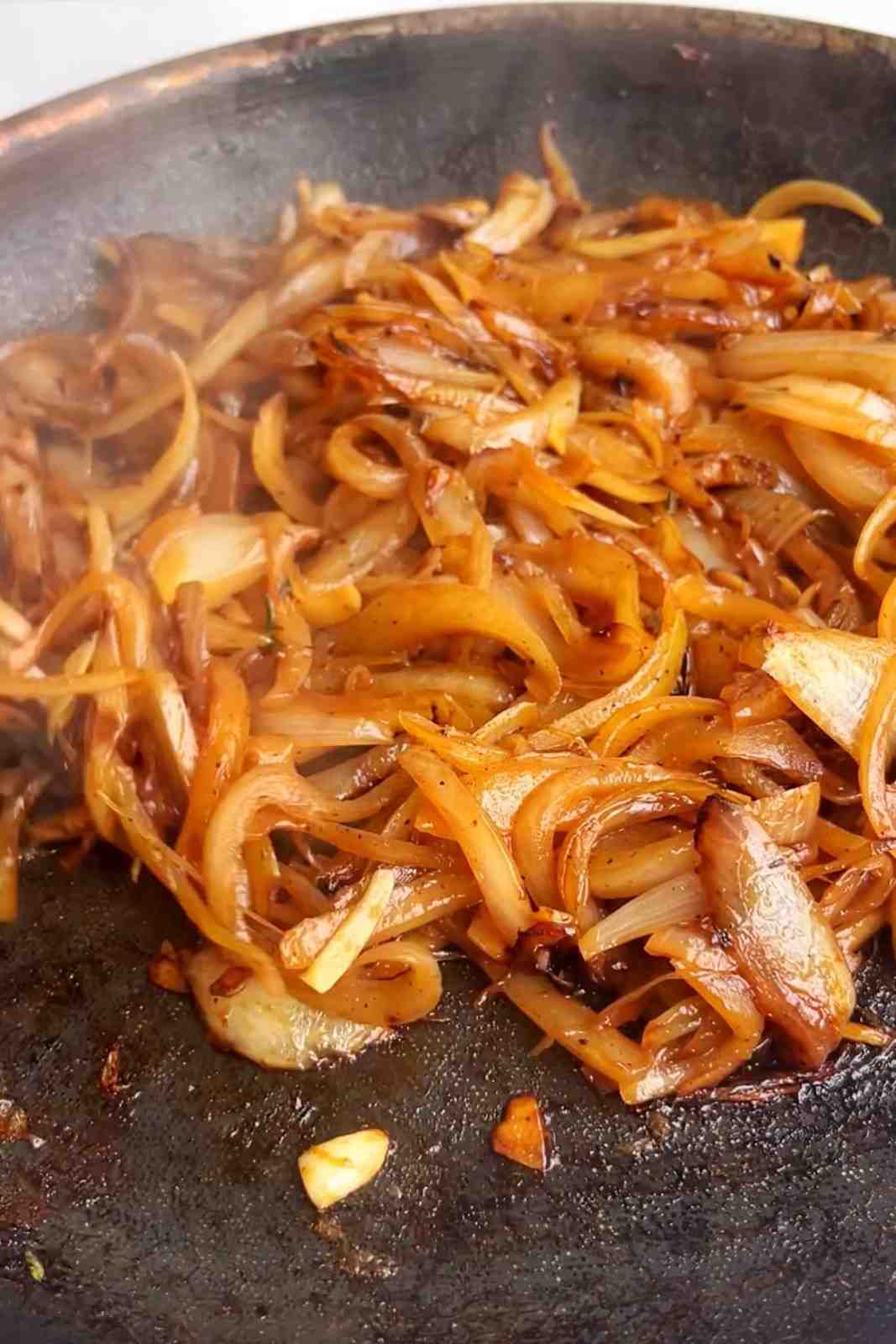 Deep golden caramelized onions slow-cooked in a skillet until jammy and sweet, a rich baked potato bar topping that pairs perfectly with cheddar or pulled pork.