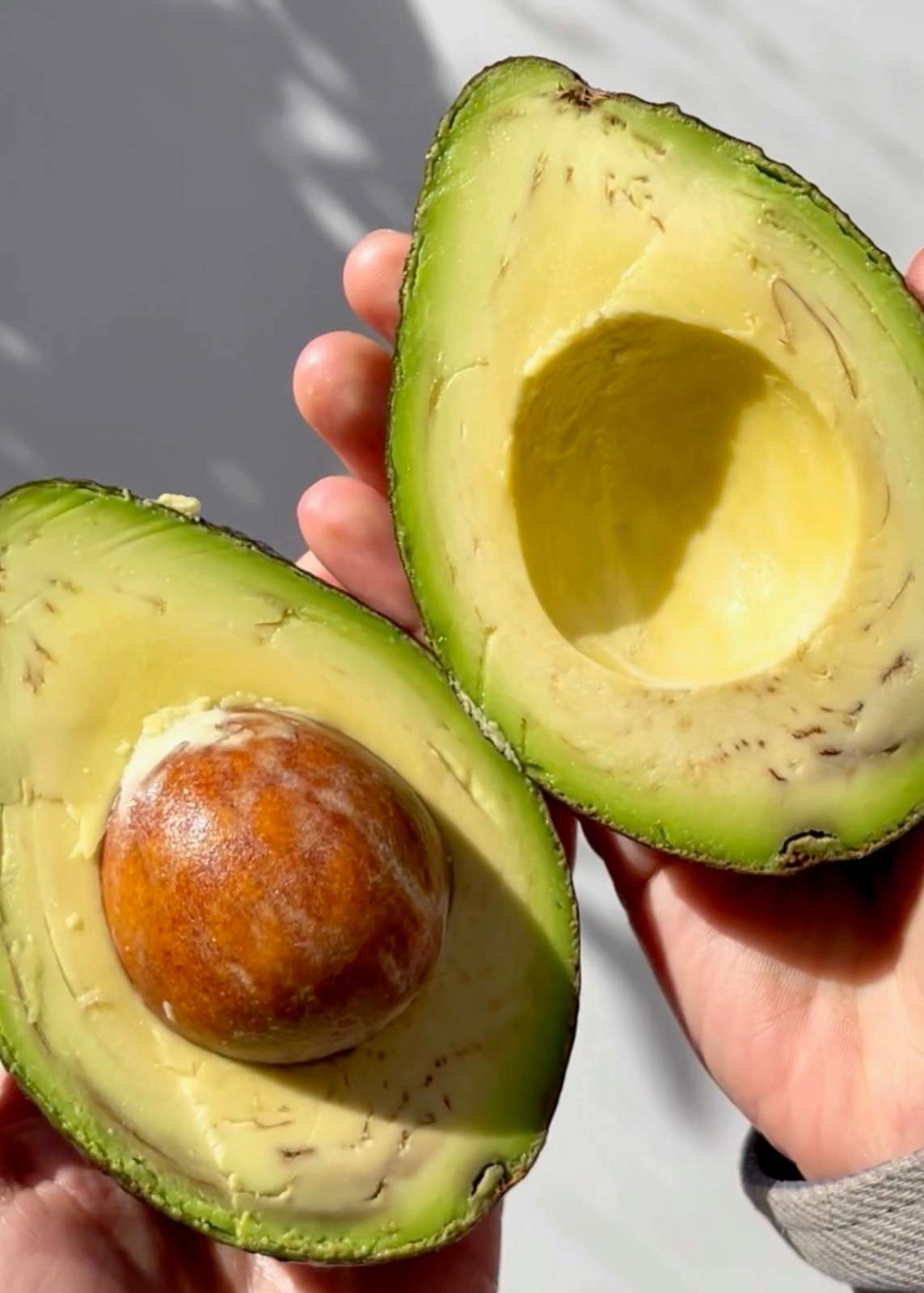 A ripe avocado split in half showing the creamy green flesh and pit, ready to be diced or mashed into guacamole for a baked potato bar.