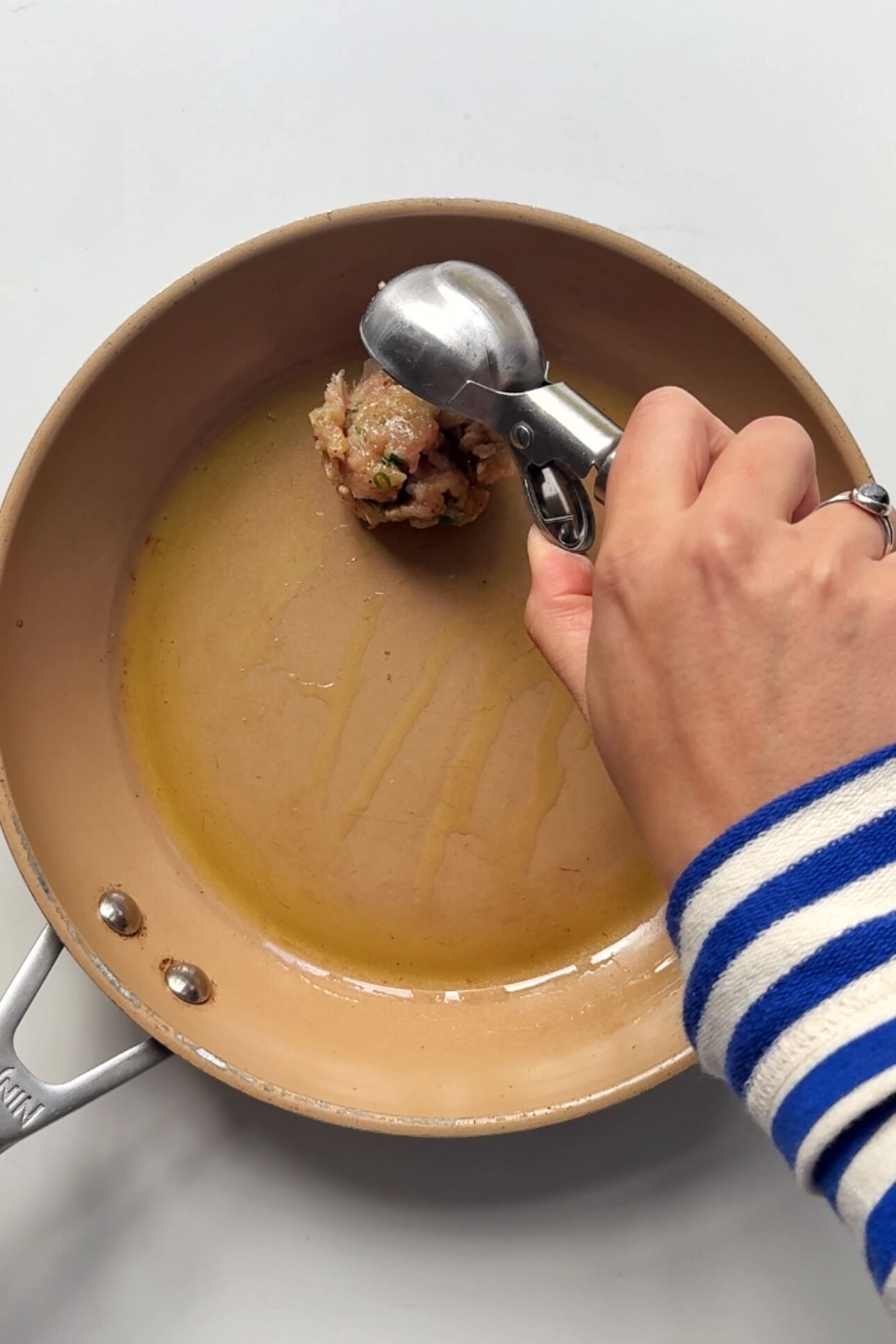 Scooping dumpling filling onto a nonstick pan.